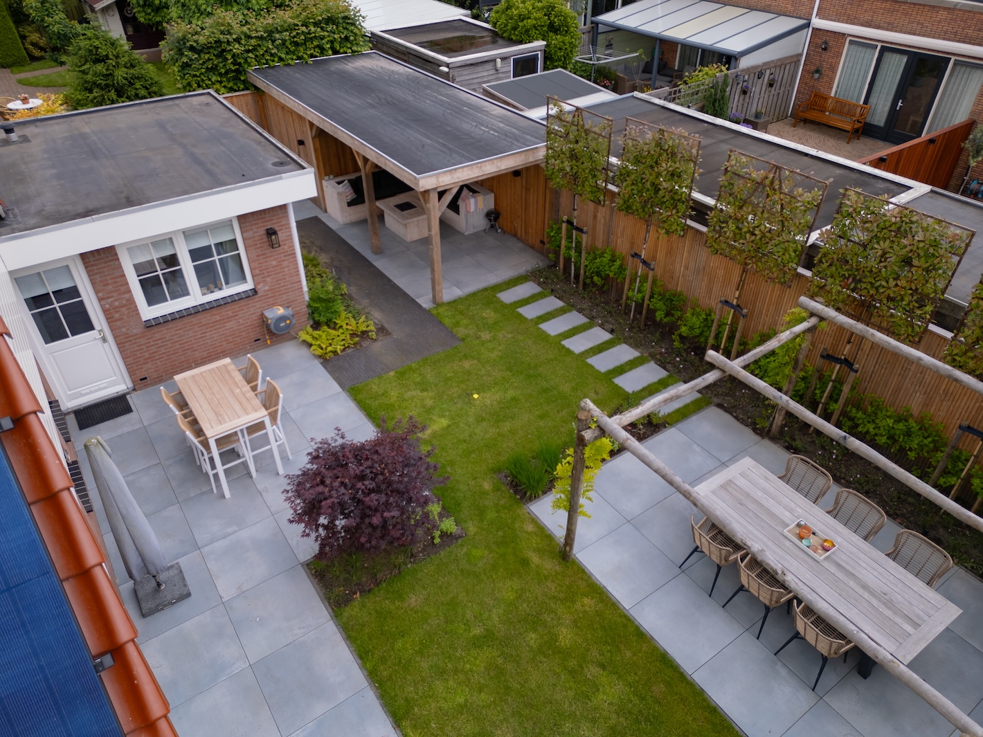 Overzicht van de vernieuwde tuin met twee terrassen en gazon, gerealiseerd door hovenier Snijers Tuinen.