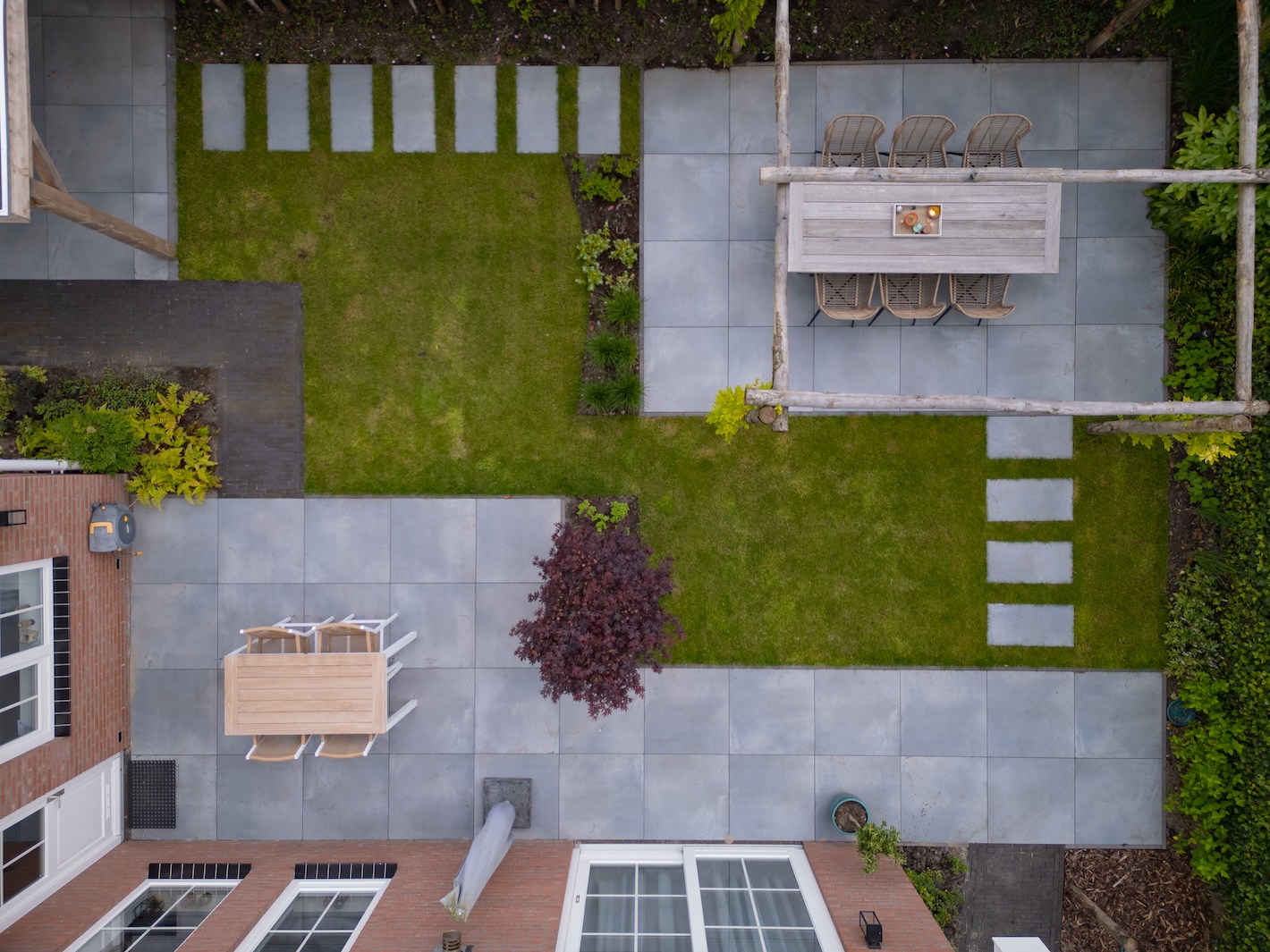 Luchtfoto van een strak ontworpen tuin met stapstenen en terrassen, gerealiseerd door Snijers Tuinen.