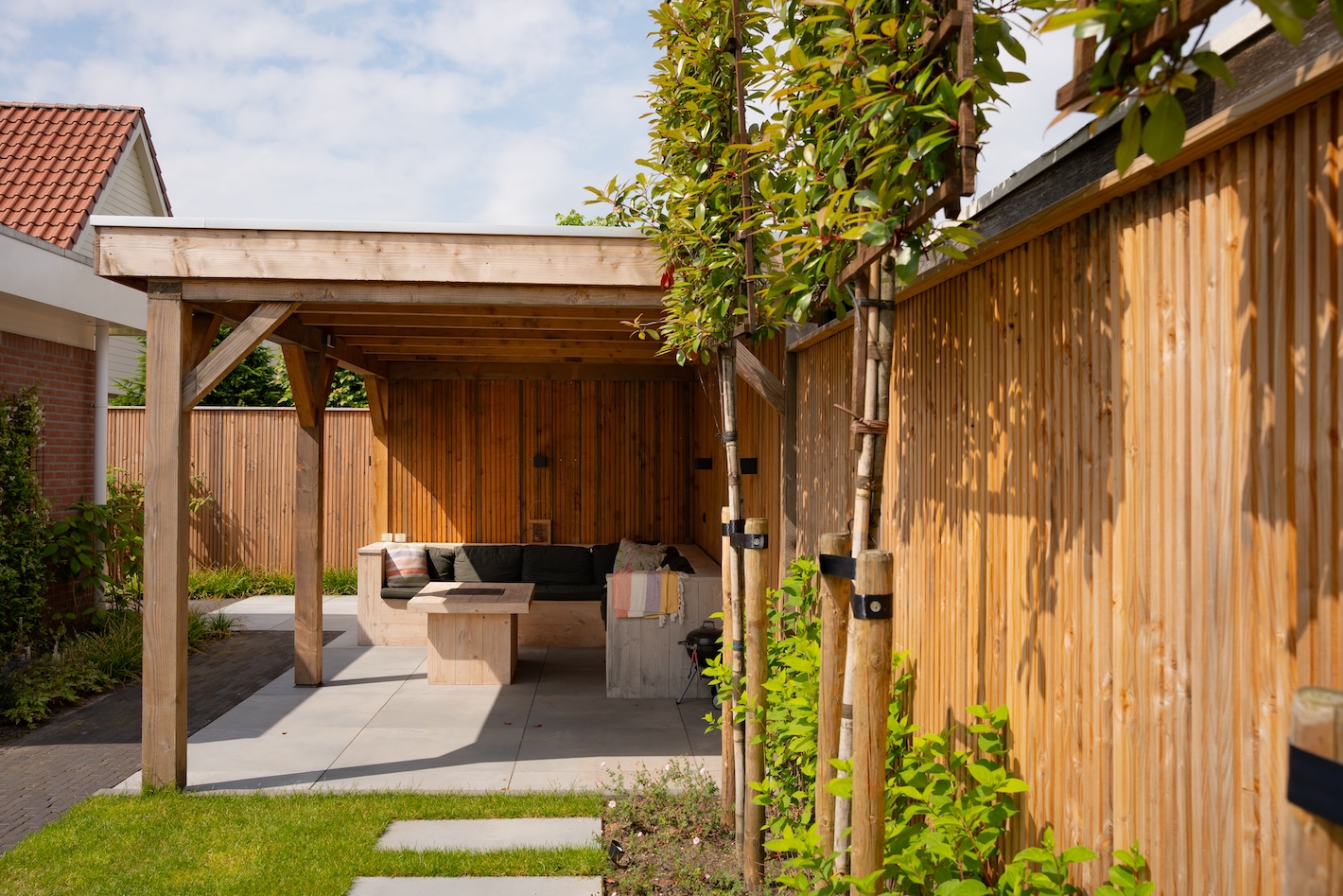 Gezellige overkapping en moderne lounge in een tuinproject uitgevoerd door Snijers Tuinen in Zeewolde.