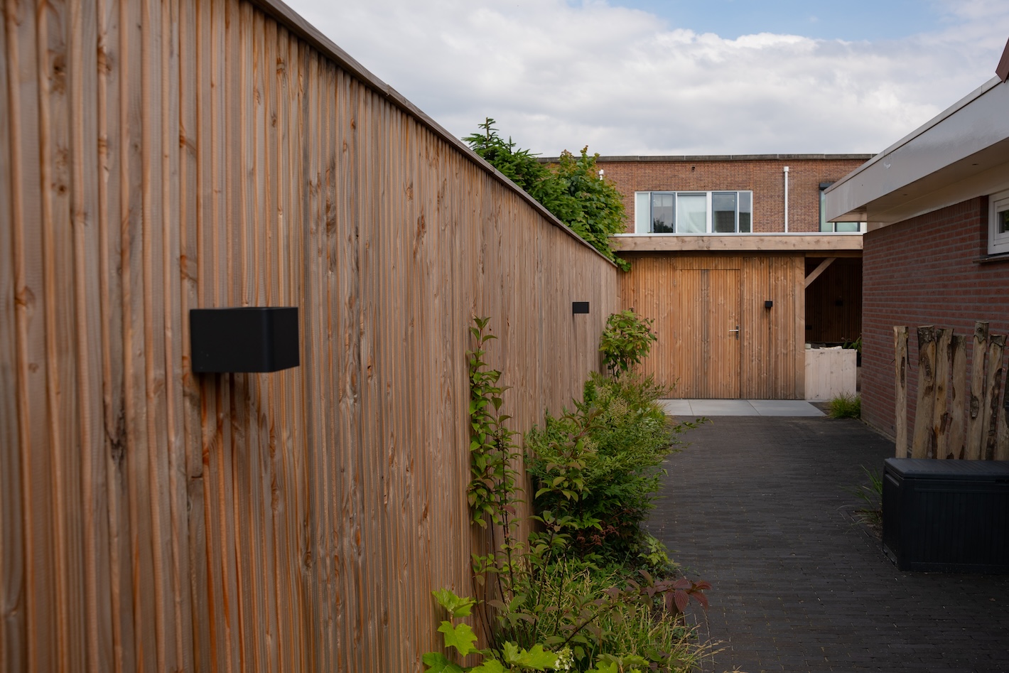 Lang tuinpad met nieuwe houten schutting, onderdeel van een tuinrenovatie door Snijers Tuinen in Zeewolde.