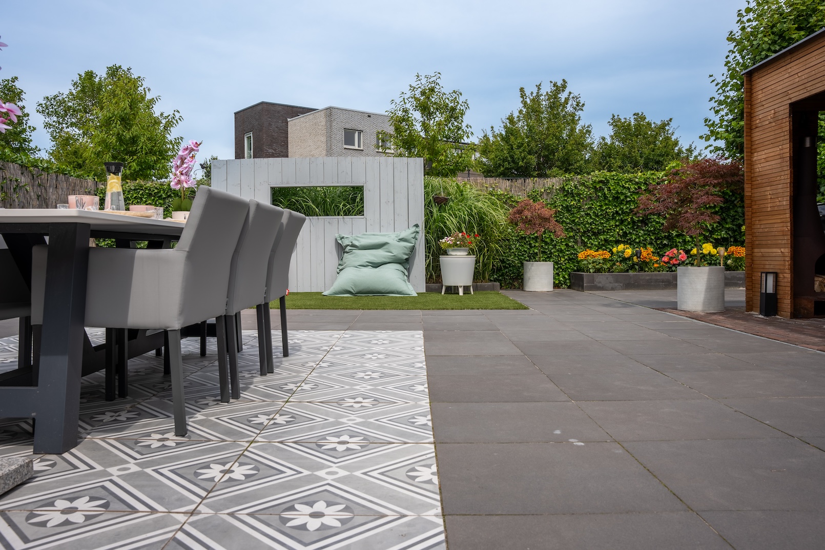 Een gedetailleerd beeld van het buiteneetgedeelte op het betegelde terras. De tafel is gedekt met verschillende gerechten en roze bloemstukken, wat zorgt voor een gastvrije sfeer voor buitenmaaltijden.